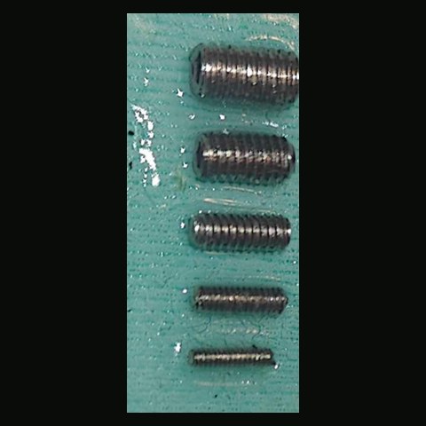 Photograph of the five set screws, M3 down to M1, on green tape